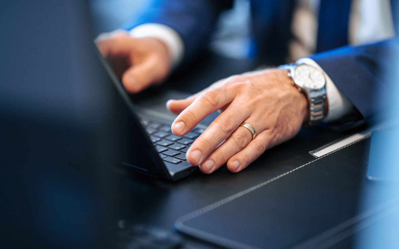 Hand an Laptop auf Schreibtisch